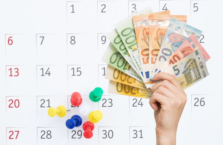 calendario con puntine che segnano date e mano con banconote euro