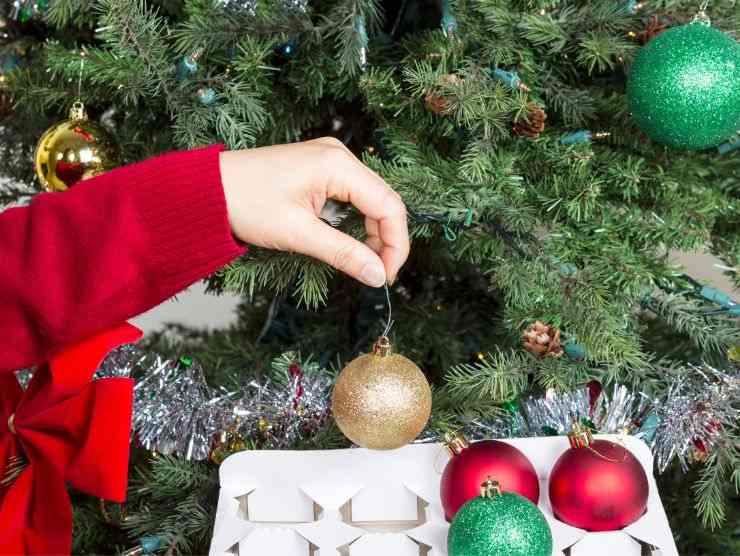 donna toglie palline dall'albero 